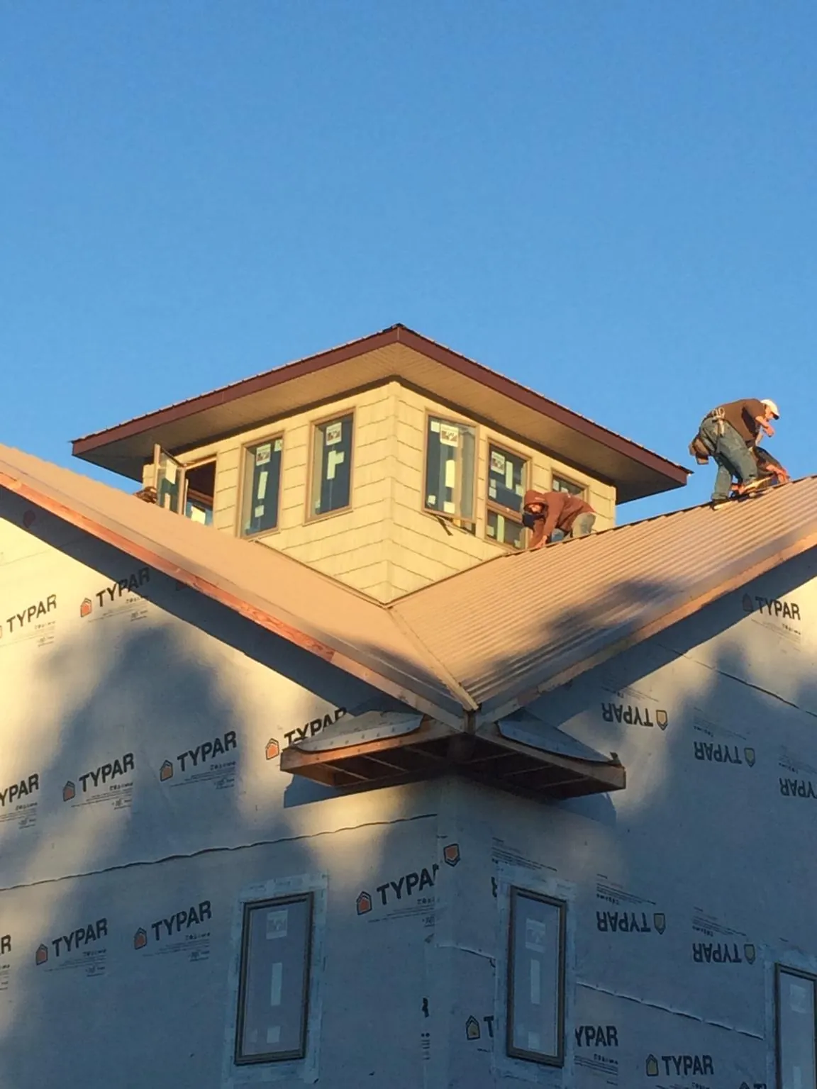 Roofers working around a rooftop cupola on a new metal roof at sunset — Roof Waterproofing in Sun Valley by Roofing Brothers